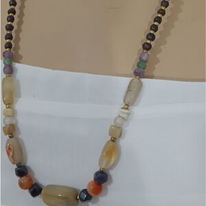 Long necklace made of various stone beads and small wooden beads going up the